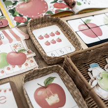 Load image into Gallery viewer, A close-up of children's educational play materials featuring red apples, numbers, and letters, arranged in woven baskets on a wooden surface.