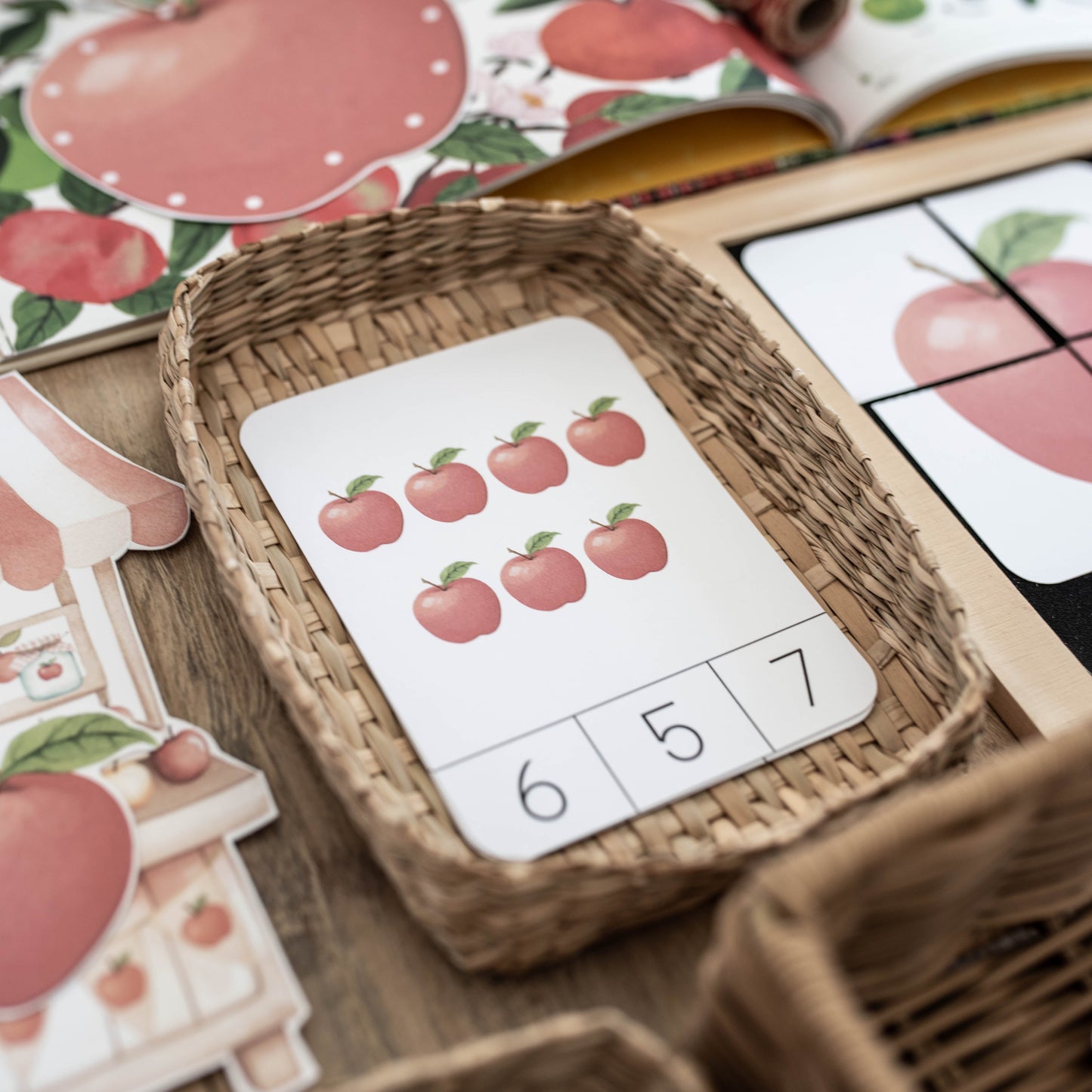 A close-up of a children's counting toy with apple-themed cards and woven baskets on a wooden surface.