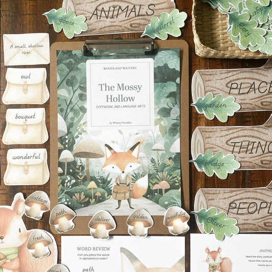 A styled flat-lay of a woodland-themed educational or craft kit on a dark wood background, featuring a central book cover titled 'The Mossy Hollow' with a fox illustration, wooden sign pieces reading words like 'ANIMALS', 'PLACE', 'THING', and 'PEOPLE', leaf stickers, small wooden cups, and printed cards.
