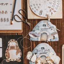 Load image into Gallery viewer, A collection of printable learning activities related to Arctic animals, laid out on a wooden surface. Activities include cutting and lacing cards, puzzles, and coloring pages.

