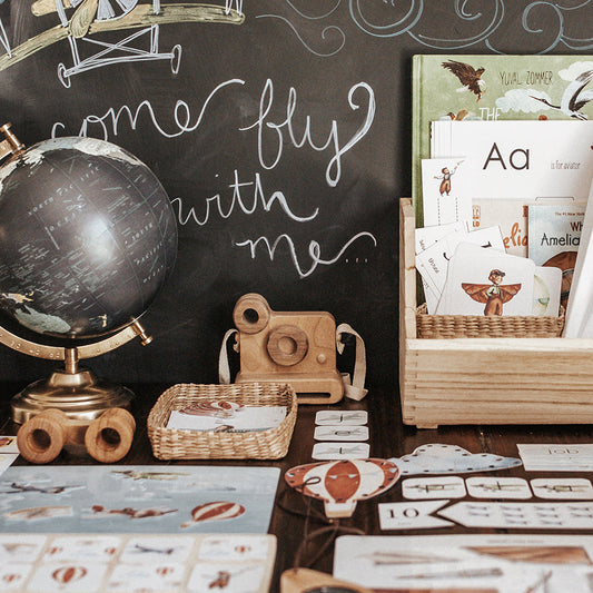 A display of educational materials related to an aviation theme, including books, printouts, and a globe, arranged on a table.