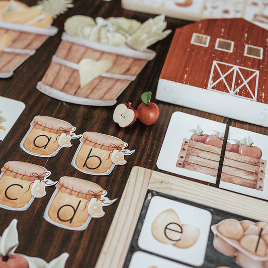 Printed educational activity sheets laid out on a table, featuring various learning exercises such as alphabet sheets and number matching games.